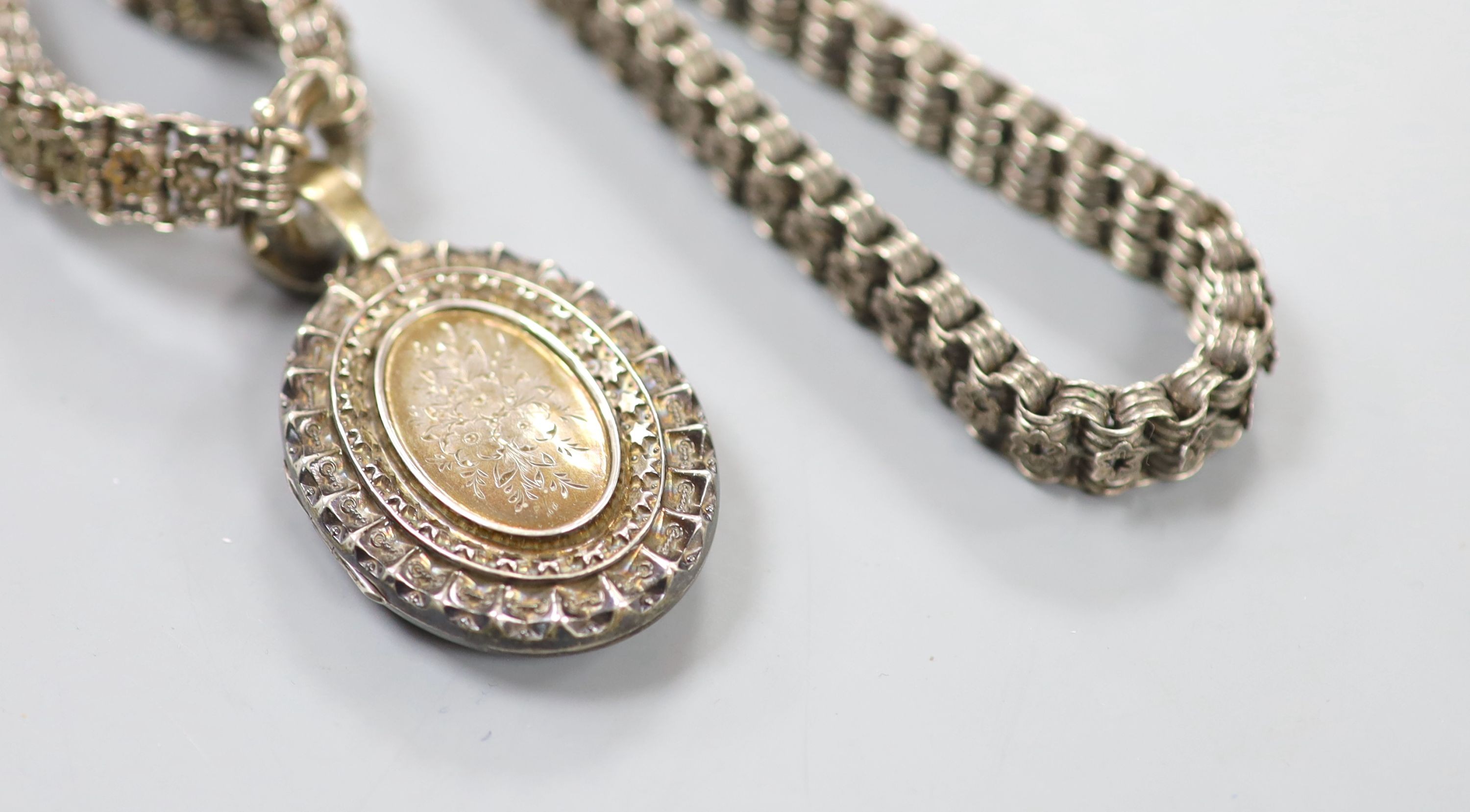 A late Victorian silver oval locket, 45mm, on a pierced white metal chain, 43cm.